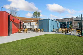 A brightly colored building with a red and blue exterior and a sign that reads "The Parl" sits next to a grassy area with picnic tables.