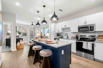 A modern kitchen with a dark blue island and white cabinets.