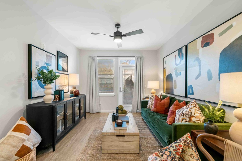 A living room with a green couch, a wooden coffee table, and a ceiling fan.