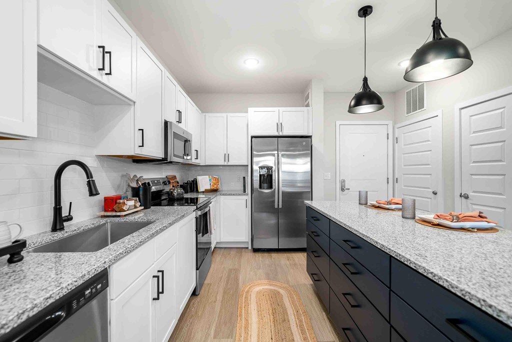 A modern kitchen with white cabinets and a wooden floor.