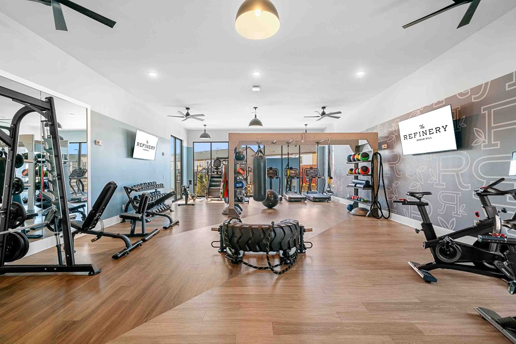 A gym with a variety of equipment including treadmills, weights, and exercise bikes.