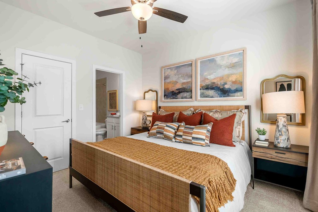 A bedroom with a bed, nightstands, and a ceiling fan.