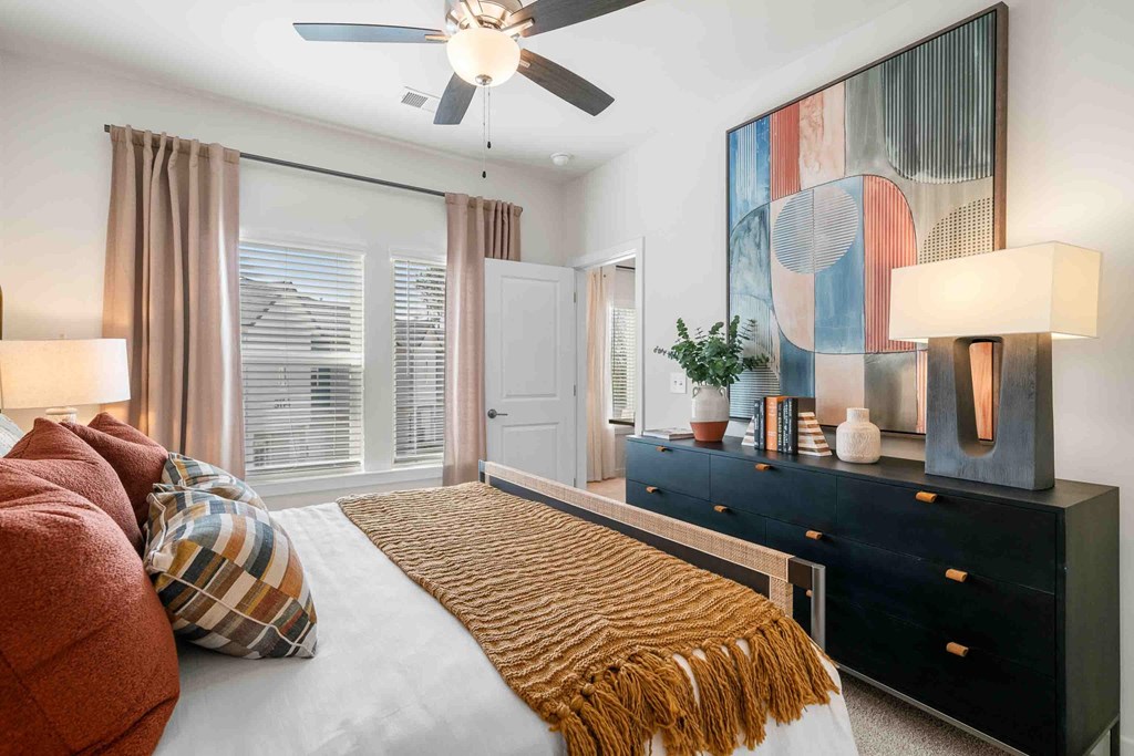 A bedroom with a bed, a dresser, and a painting on the wall.