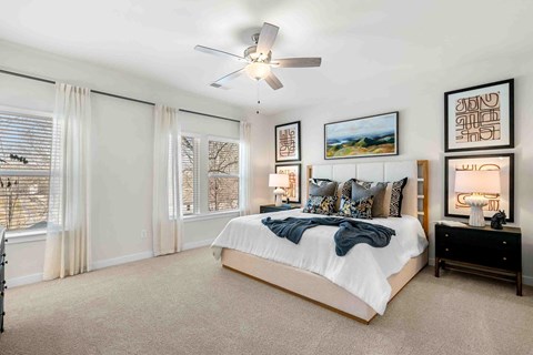 Dog-Friendly Homes for Rent in Sugar Hill, GA - The Refinery - Bedroom with Carpet Flooring, Large Bed, Nighstands with Lamps, Framed Wall Art, Ceiling Fan, and Large Windows.