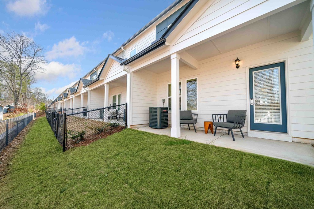 A white house with a black fence and a green lawn.