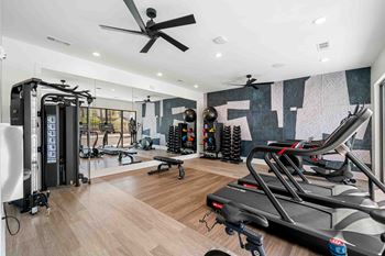 A home gym with a treadmill, weights, and exercise equipment.