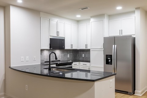 A kitchen with a black counter top and stainless steel appliances.