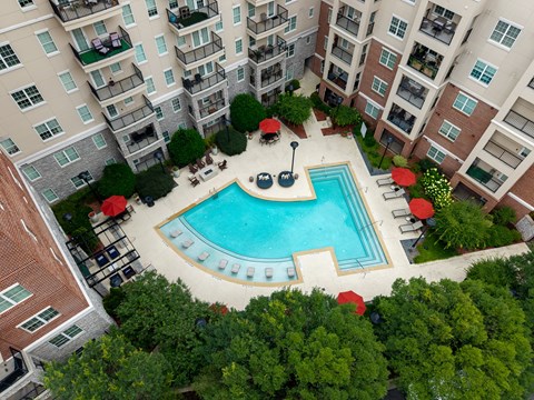 An aerial view of a pool surrounded by trees and chairs.