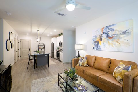 A living room with a brown couch and a painting on the wall.