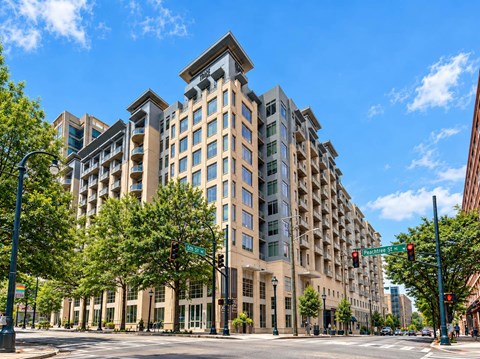 A large, modern building with many windows is situated on a street corner.