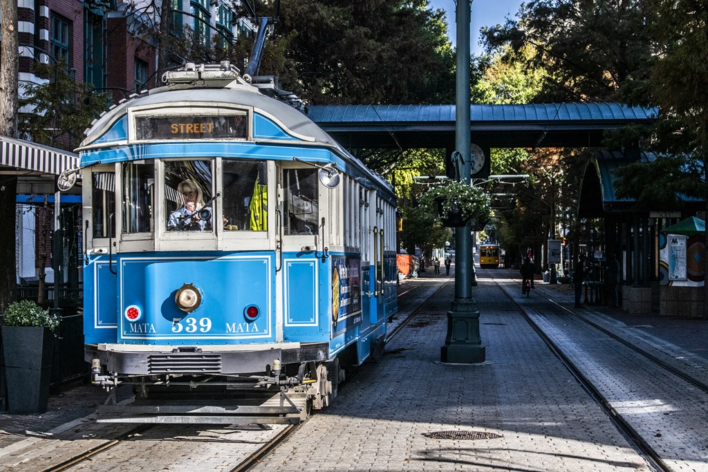 a blue and white trolley car on a city street
