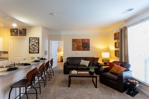 A living room with a black couch and a painting on the wall.