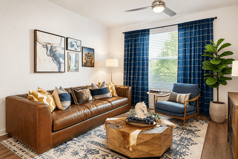 A living room with a brown leather couch, a coffee table with a gift box on it, a blue chair, and a ceiling fan.