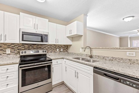 A kitchen with white cabinets and a granite countertop.