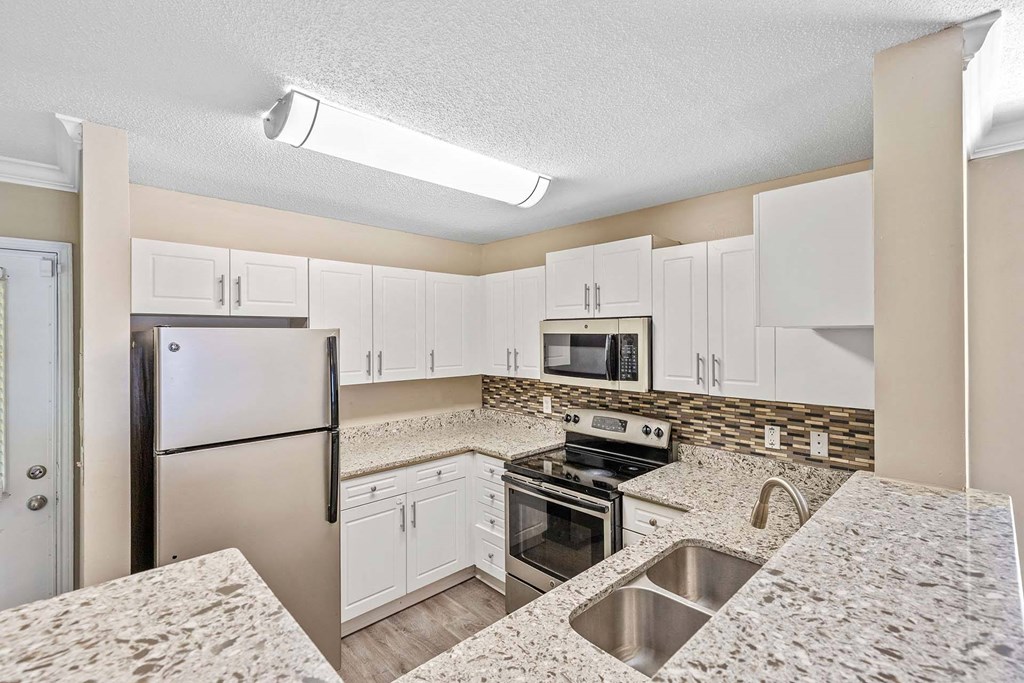 A kitchen with a refrigerator, oven, and microwave.
