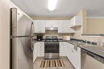 A kitchen with a stainless steel refrigerator and white cabinets.