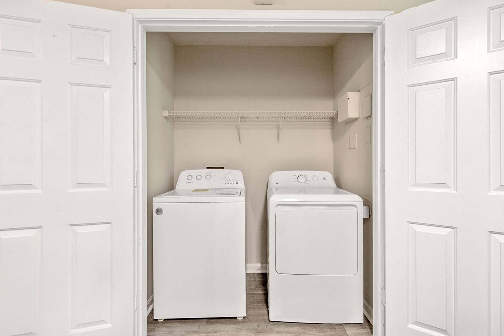 Two white washing machines in a small laundry room.