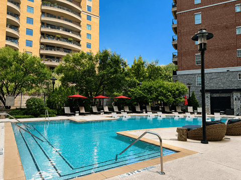 A swimming pool surrounded by trees and chairs.