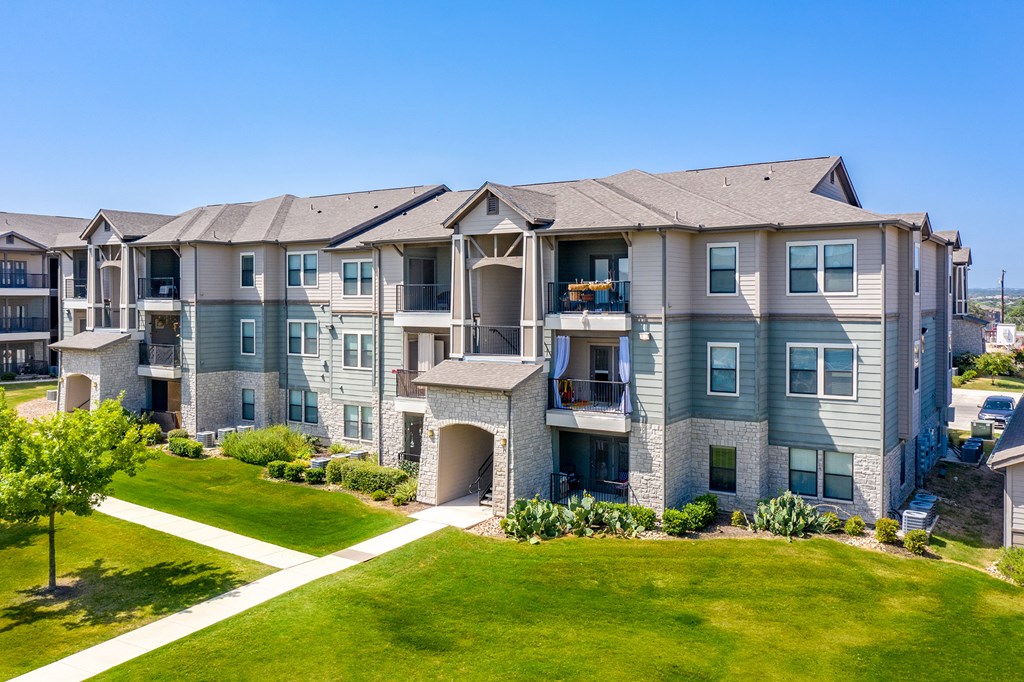 an apartment building with green lawns and a blue sky