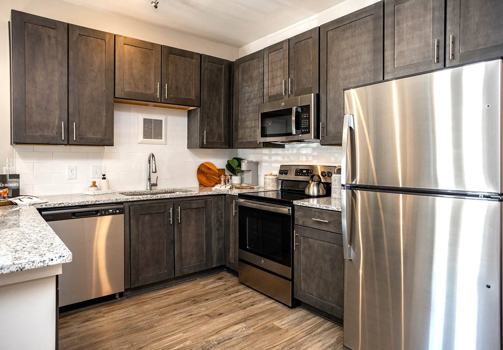 a kitchen with dark cabinets and stainless steel appliances