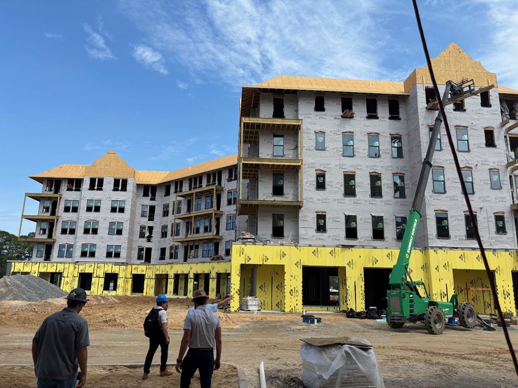 Three construction workers are standing in front of a building under construction.