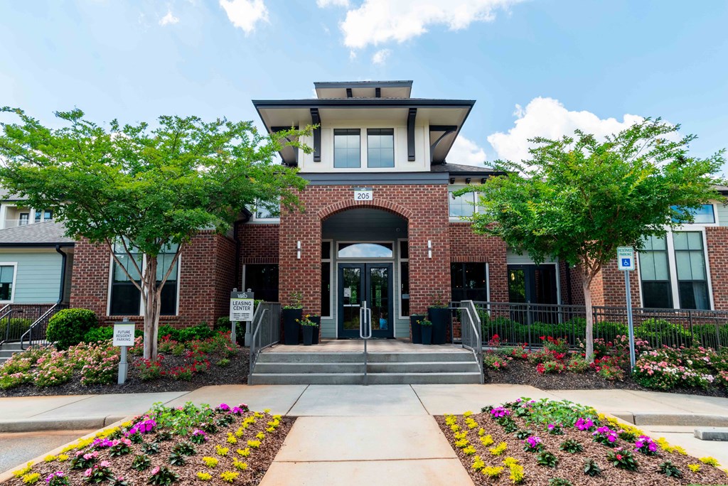 the front entrance of a brick building with trees and flowers