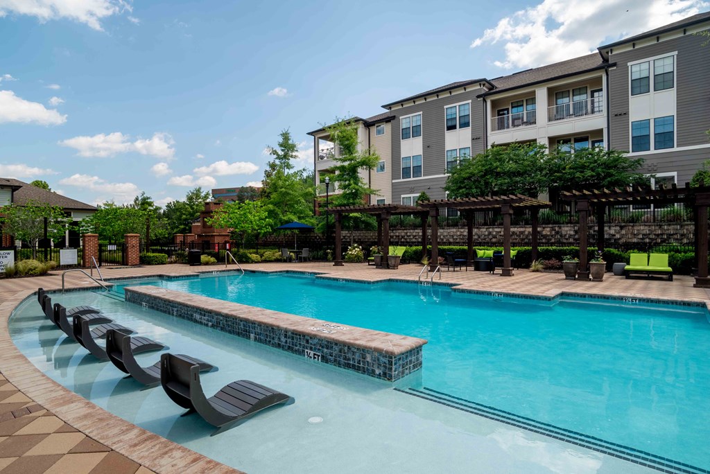 One-BR Apartments in Greenville, SC - Velo Verdae - Pool with Submerged Sun Lounge Chairs, Gazebos with Loungers, and Umbrella Table with Chairs