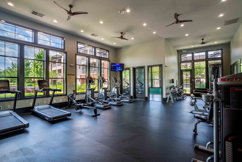a gym with cardio equipment and windows in a building