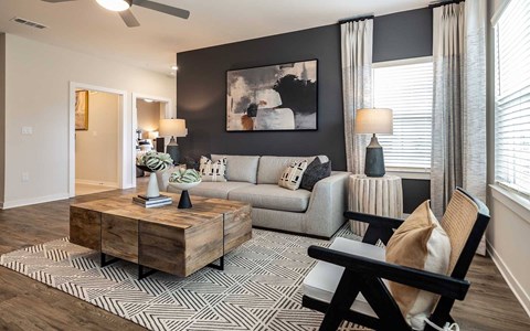 A living room with a grey couch, a coffee table, and a painting on the wall.