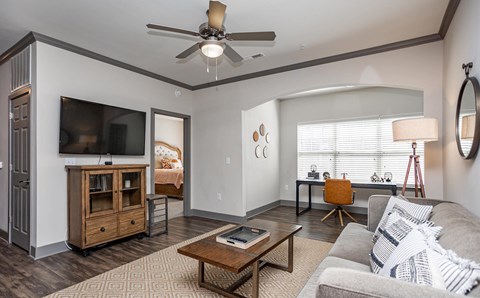 a living room with a ceiling fan and a tv