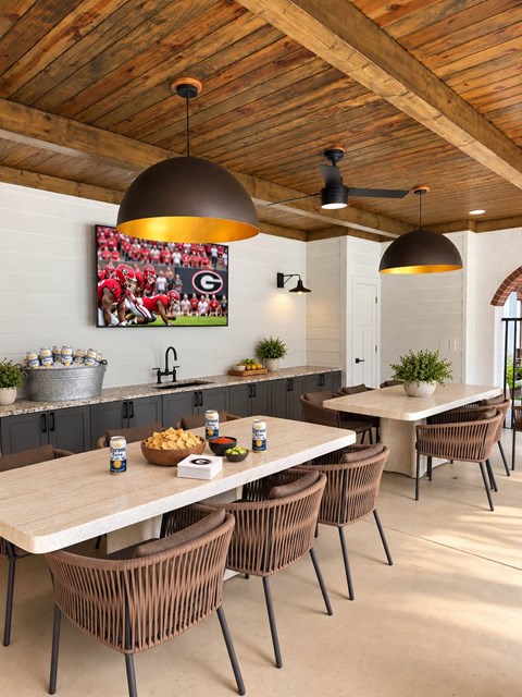 A modern dining room with a wooden ceiling and a large TV screen.