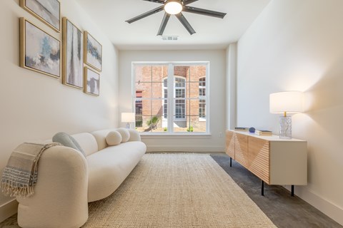A living room with a white couch and a ceiling fan.