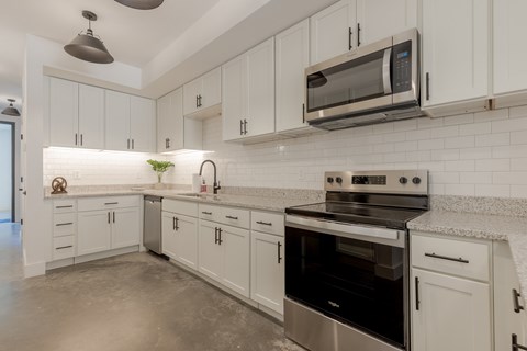 A modern kitchen with white cabinets and stainless steel appliances.