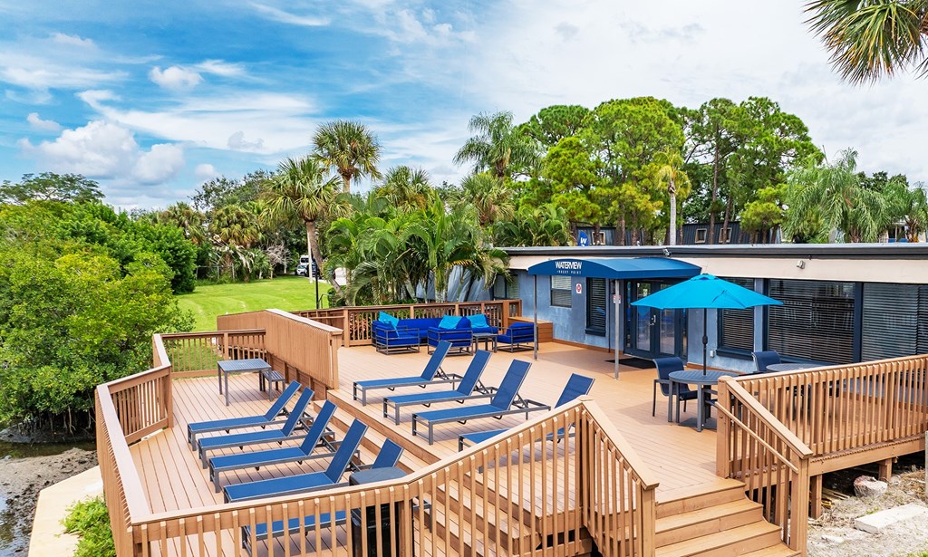 A wooden deck with blue lounge chairs and a blue umbrella at Waterview at Rocky Point, Tampa, FL