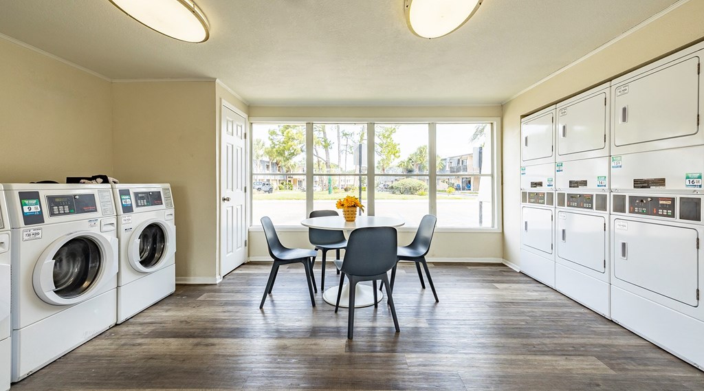 A laundry room with a table and chairs in the middle at Waterview at Rocky Point, Tampa, FL