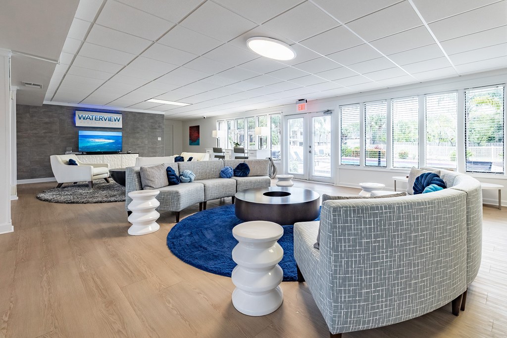 A living room with a blue rug and white furniture at Waterview at Rocky Point, Tampa, FL