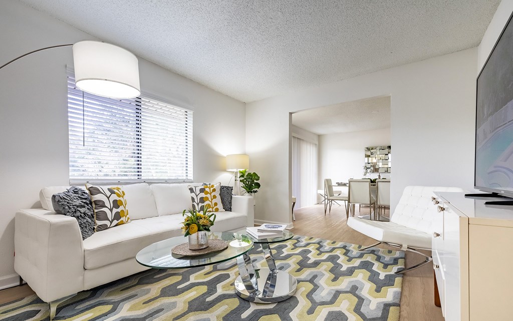 A living room with a white couch and a glass coffee table at Waterview at Rocky Point, Tampa, FL