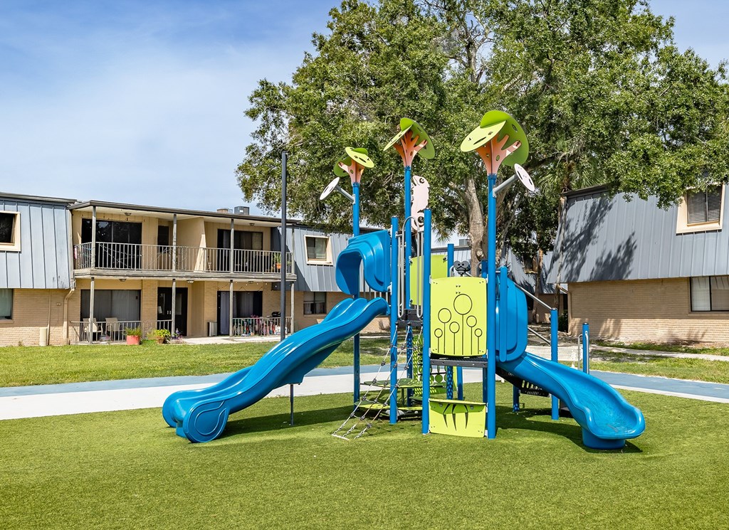 A playground with a blue slide and yellow and green towers at Waterview at Rocky Point, Tampa, FL