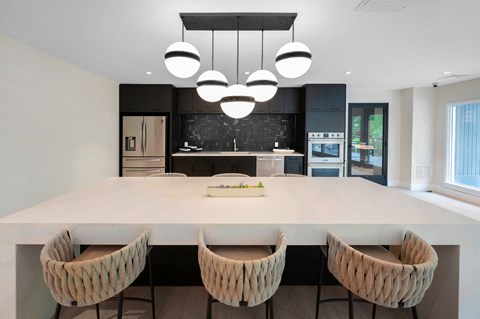 a kitchen with a large island with three chairs and a black and white