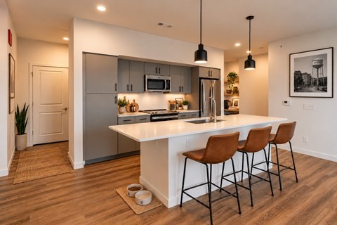 A modern kitchen with a white island and brown chairs.