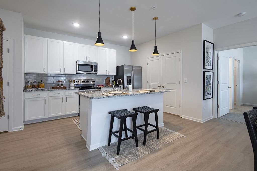 a kitchen with white cabinets and a large island with two stools