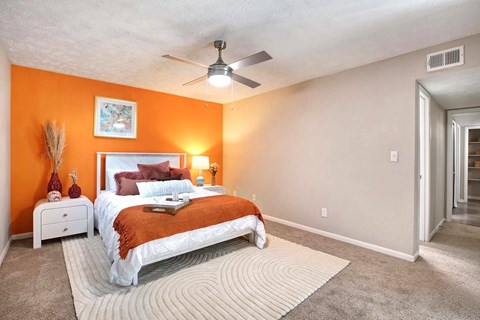 A bedroom with orange walls and a white bed.