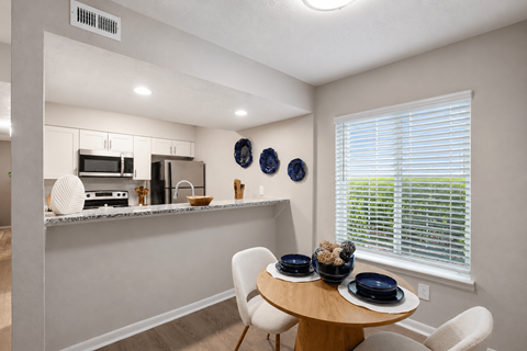 A kitchen with a table and chairs by a window.