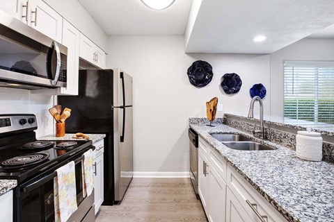 A kitchen with granite countertops and a black refrigerator.
