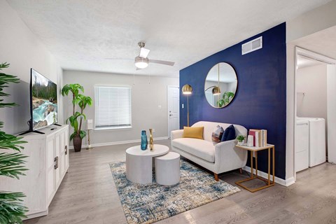 A living room with a white couch and a TV on a cabinet.