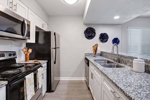 A kitchen with granite countertops and a black stove top oven.
