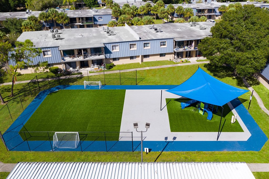 a blue tent is set up on a tennis court in front of a row of houses  at Waterview at Rocky Point, Tampa