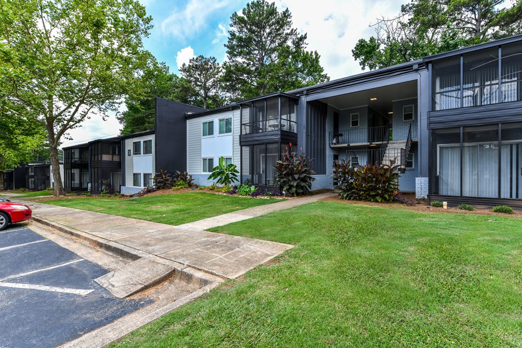 a row of apartment buildings with a grassy yard and trees in the background