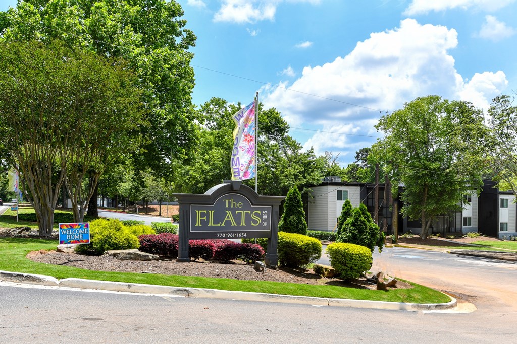 a sign that says the flats in front of trees and bushes
