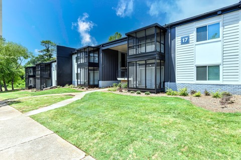 a group of houses in a row with a grassy area and trees in the background